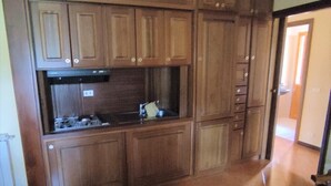 Une cuisine avec des meubles de rangement en bois, une cuisinière et un évier.