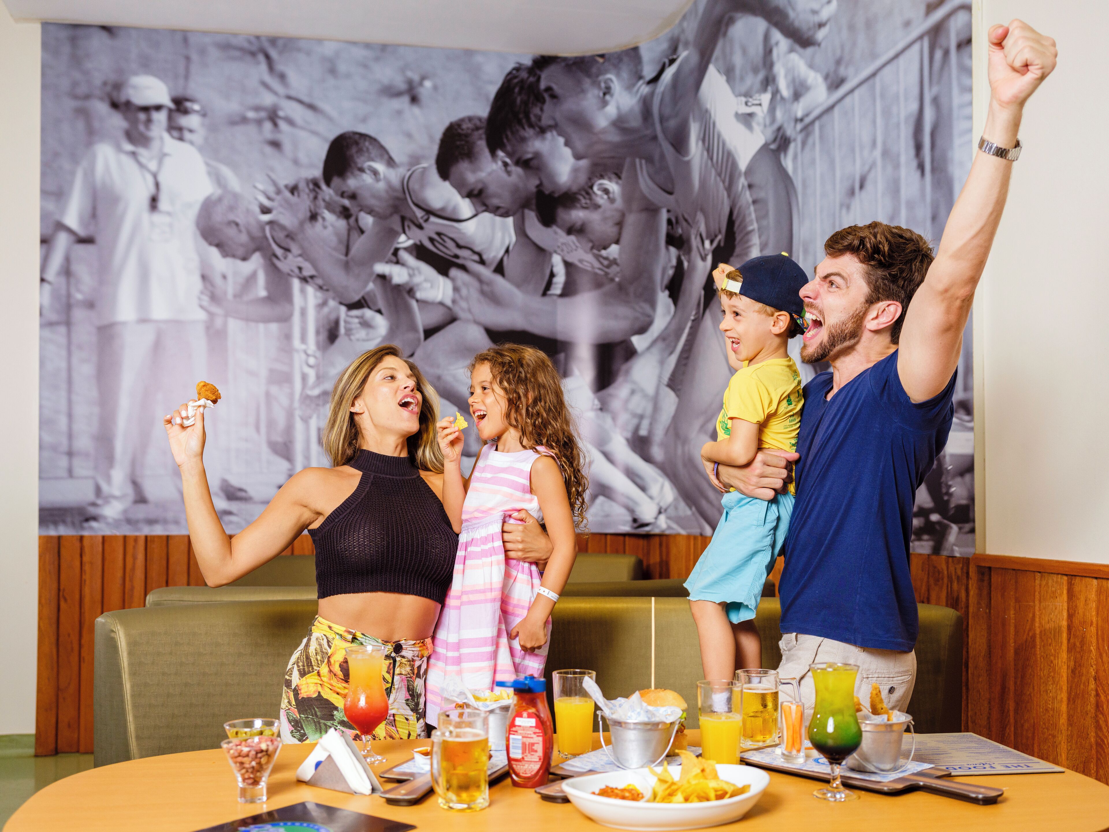 Una familia cenando en un restaurante con un cartel grande al fondo.