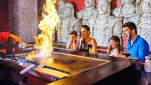 Un restaurant doté d’un grand grill et orné d’un mur de statues de guerriers en pierre.