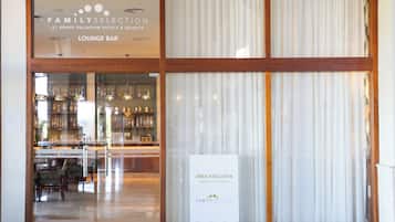 A lounge bar with a glass front, a sign indicating an exclusive area, and a bar stocked with bottles.