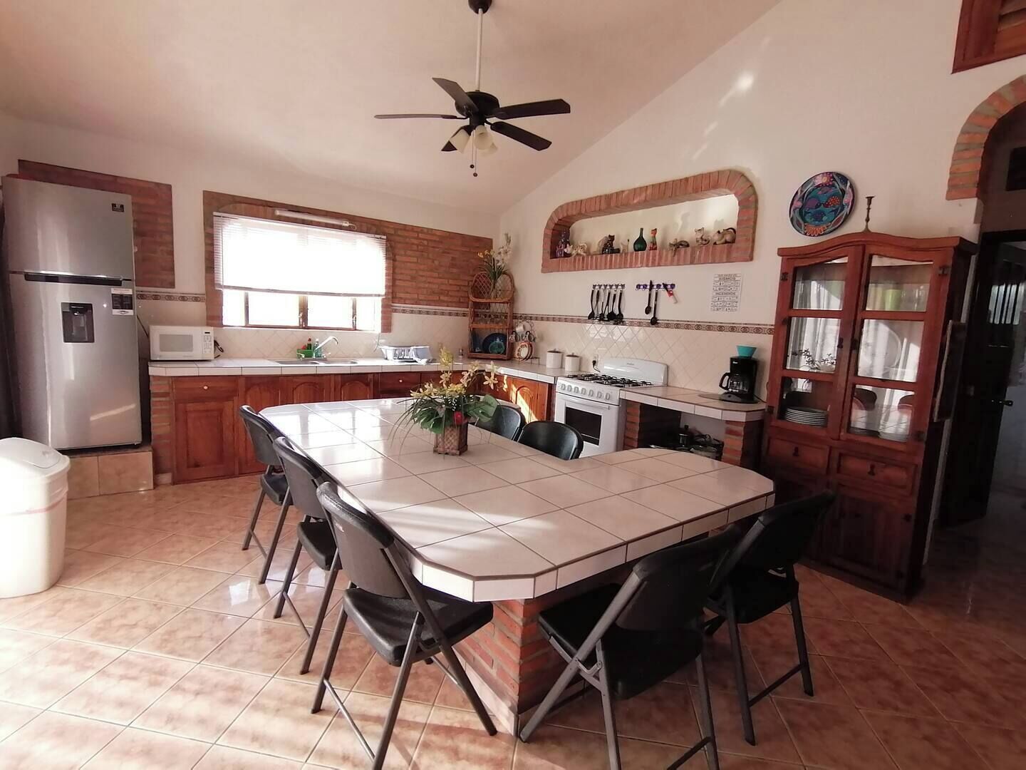 A kitchen with a central island, a refrigerator, a microwave, a sink, and a stove.