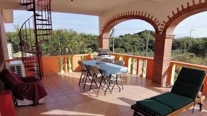 A covered outdoor area with a table and chairs, a lounge chair, and a spiral staircase. - 2bdup Casalaspalmas Puntademita (Punta de Mita)
