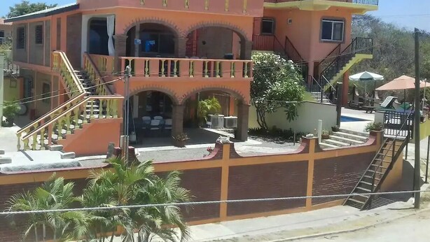 A multi-story building with a central courtyard, balconies, and a thatched roof structure. - 2bdup Casalaspalmas Puntademita (Punta de Mita)