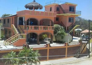 Un edificio de varios pisos con un patio central, balcones y una estructura de techo de paja.