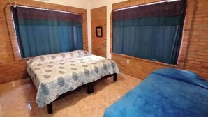 A room with a bed, a small table, and a window with curtains. - 2bdup Casalaspalmas Puntademita (Punta de Mita)