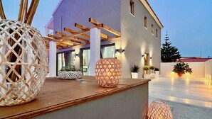 Un edificio moderno con una pérgola, zona de estar al aire libre y lámparas esféricas decorativas.