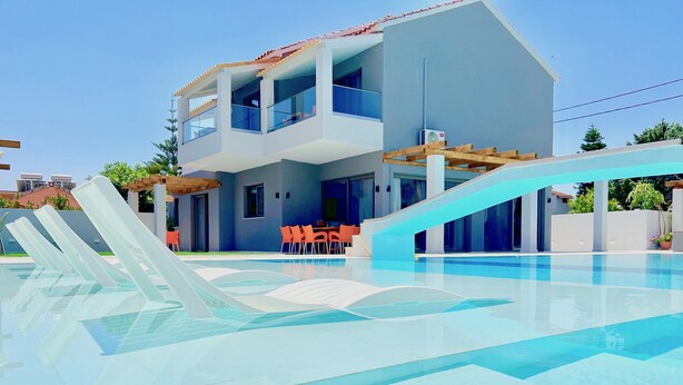 Una casa moderna de dos pisos con piscina, mobiliario exterior y una pérgola.