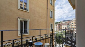 Un balcon avec une table, une cafetière et un saladier.