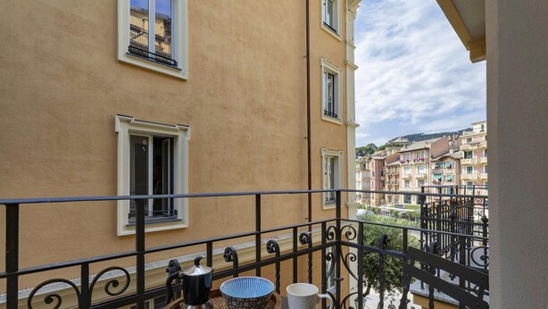 A balcony with a table, a coffee pot, and a bowl.