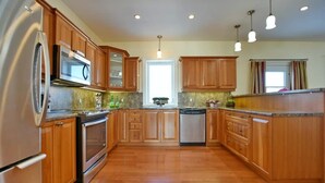 A kitchen with wooden cabinets, stainless steel appliances, and a granite countertop.