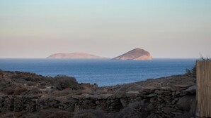 A coastal landscape with rocky terrain and a stone wall in the foreground. - Kythea Suites Kythnos (Kithnos)
