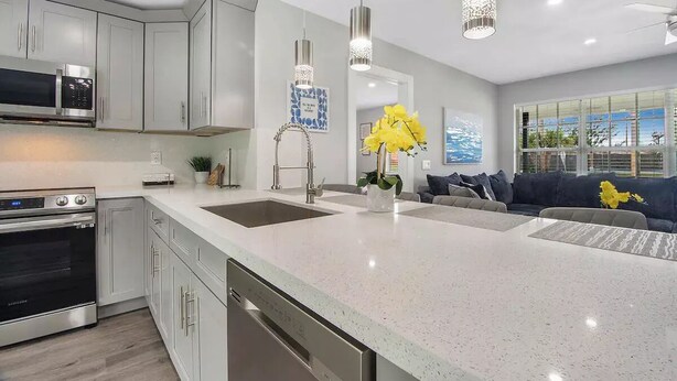 A modern kitchen with white cabinetry, stainless steel appliances, and a large island. - Modern getaway near the beach with room for a boat (West Palm Beach)