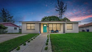 A two-story house with a green door, a pathway leading to the front, and a bench outside. - Modern getaway near the beach with room for a boat (West Palm Beach)