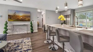 A modern kitchen with a bar area, a ceiling fan, pendant lights, and a large window with a view. - Modern getaway near the beach with room for a boat (West Palm Beach)
