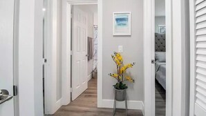 A hallway with white walls, a potted plant, and a framed picture on the wall. - Modern getaway near the beach with room for a boat (West Palm Beach)