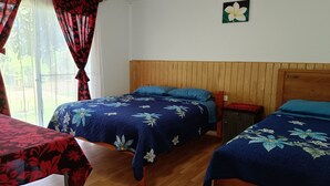 Una habitación con dos camas, cabeceros de madera, una mesita y una ventana con cortinas.