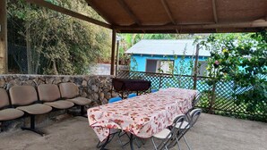 Un patio al aire libre con una mesa cubierta por un mantel floral, rodeado de sillas.