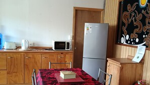 Una cocina compacta con armarios de madera, microondas, refrigerador y una mesa con sillas.