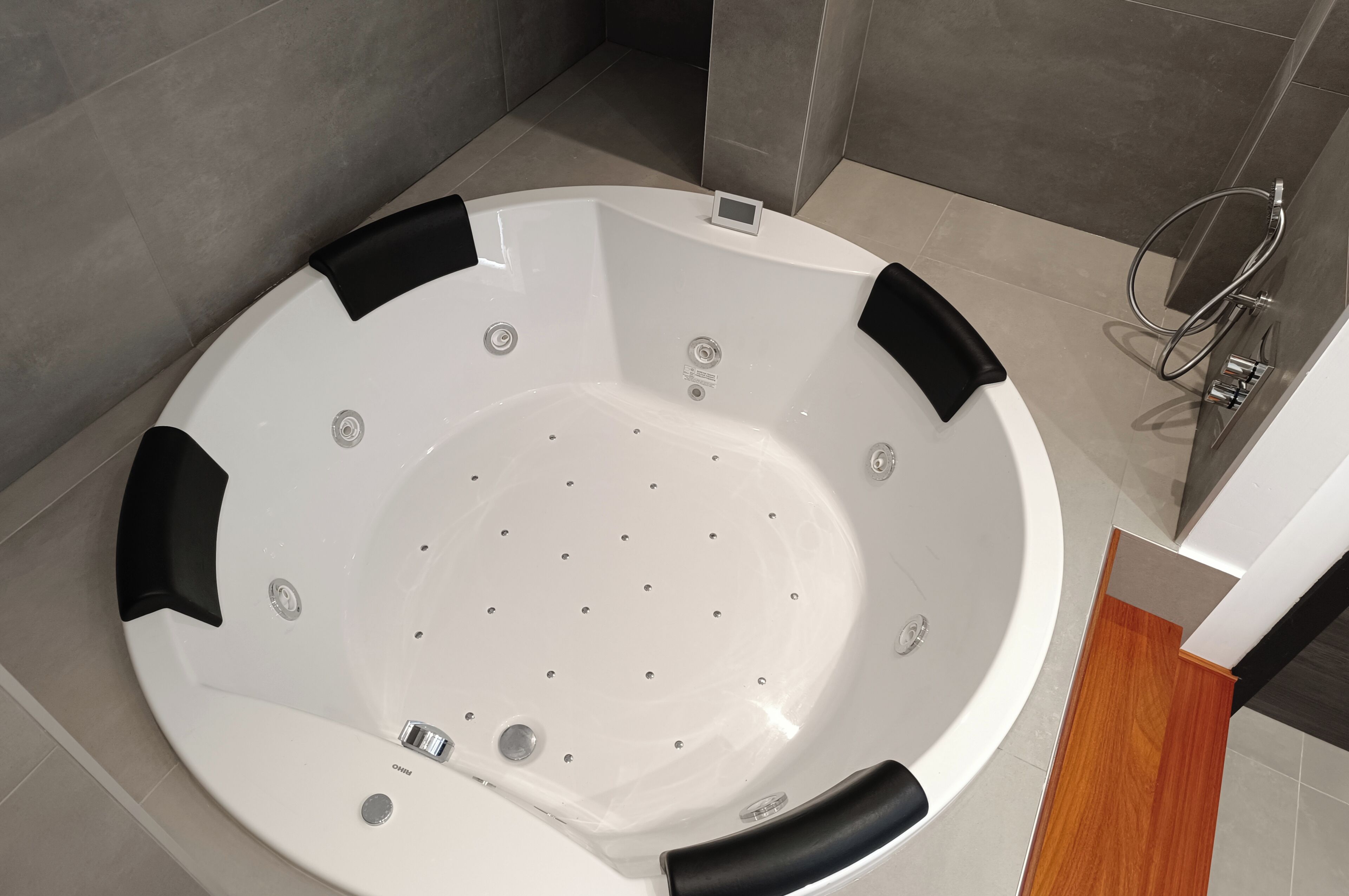 A modern bathroom with a large bathtub, a shower area, and a wooden floor.