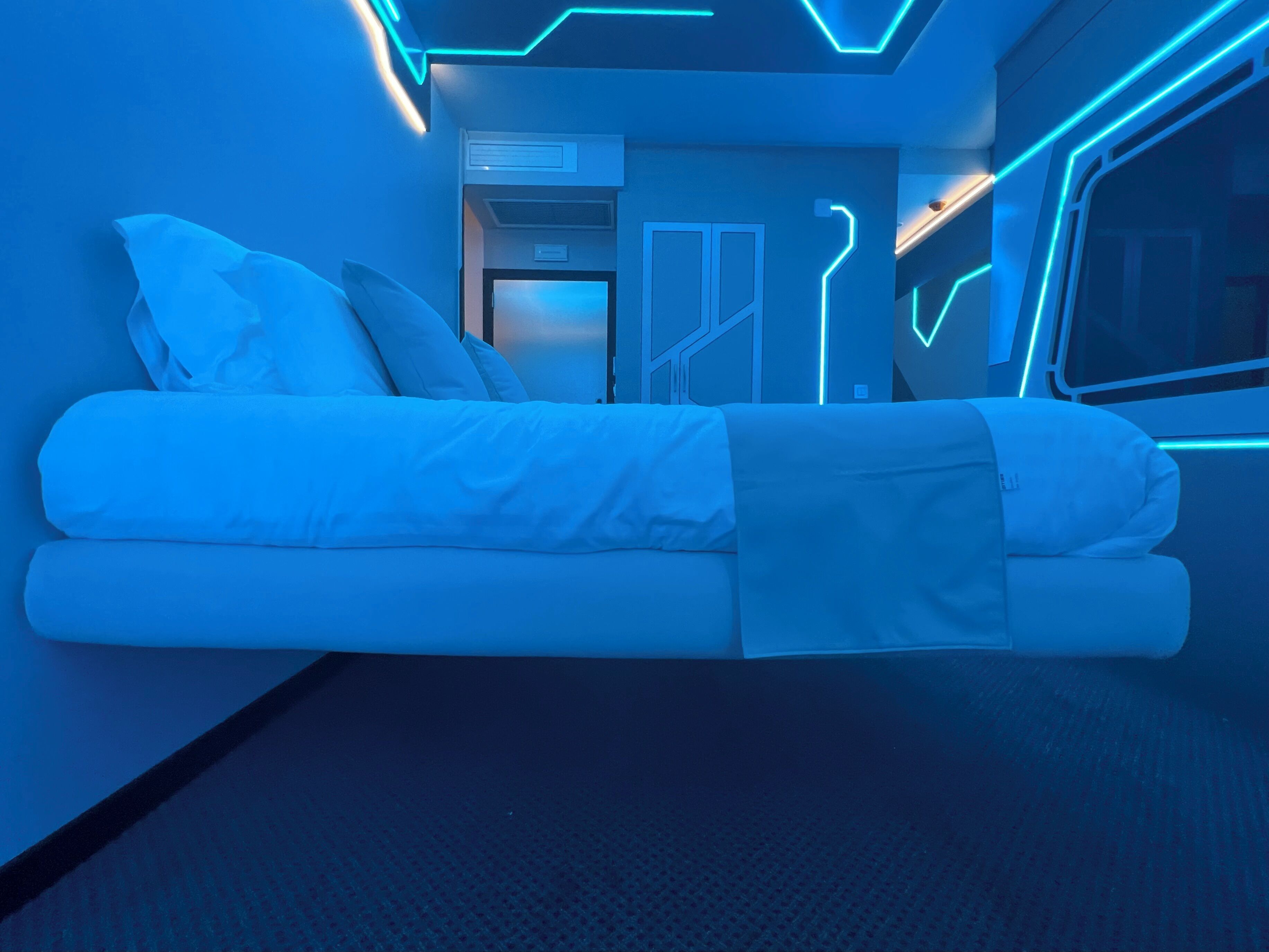 A modern room with a bed, a door, and a window.
