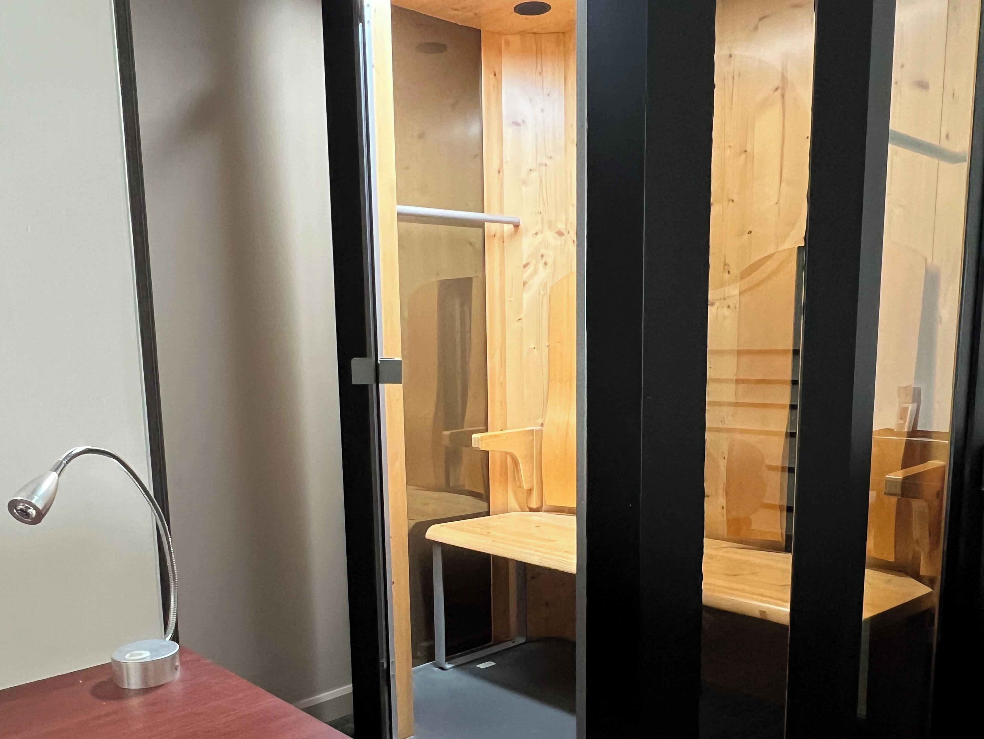 A modern bathroom with a wooden shower enclosure, a glass door, and a metal faucet on a wooden countertop.