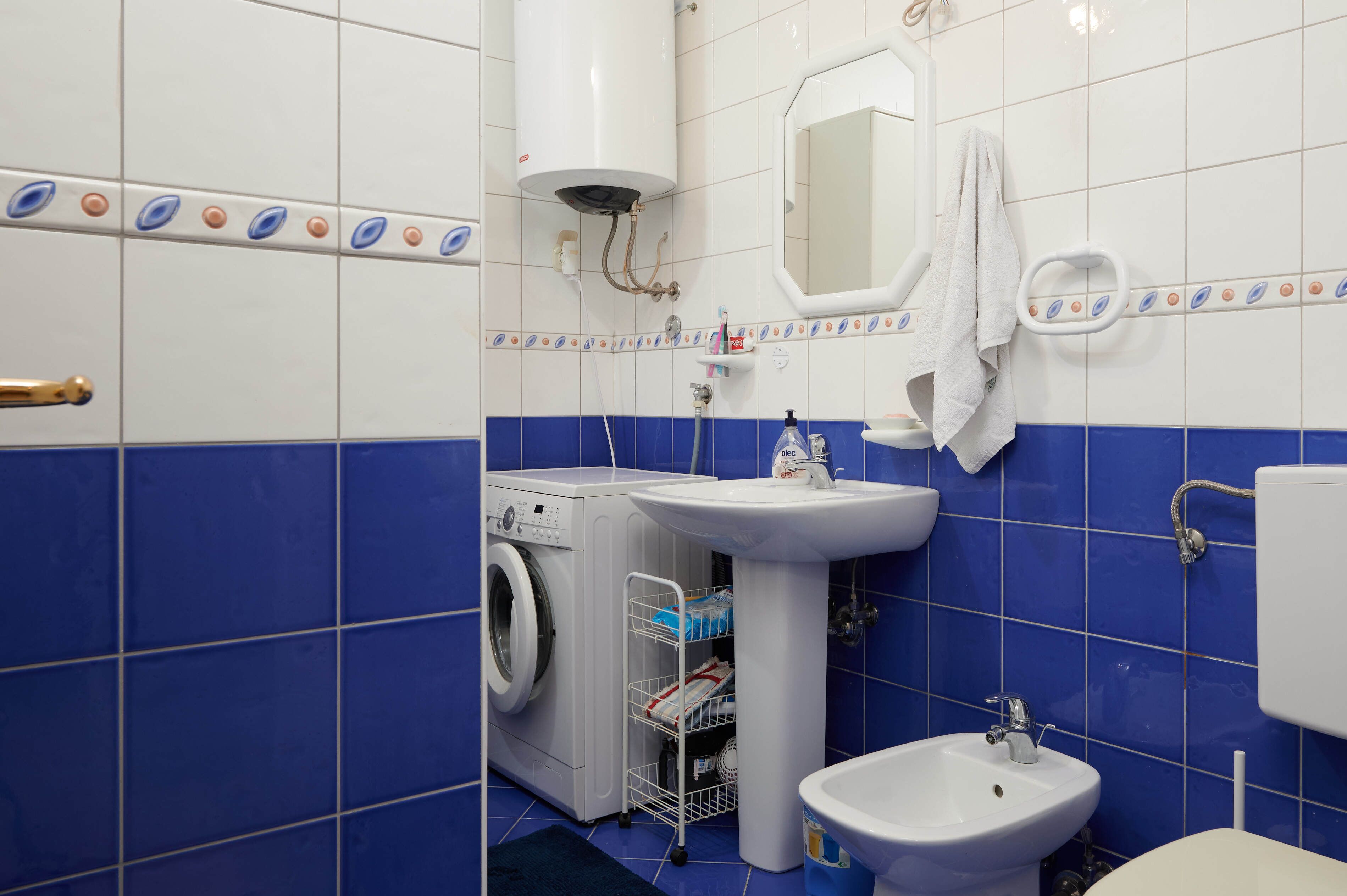 A bathroom with a washing machine, sink, and toilet.