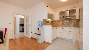 Een moderne keuken met witte kasten, een inbouwoven en een waterdispenser.
