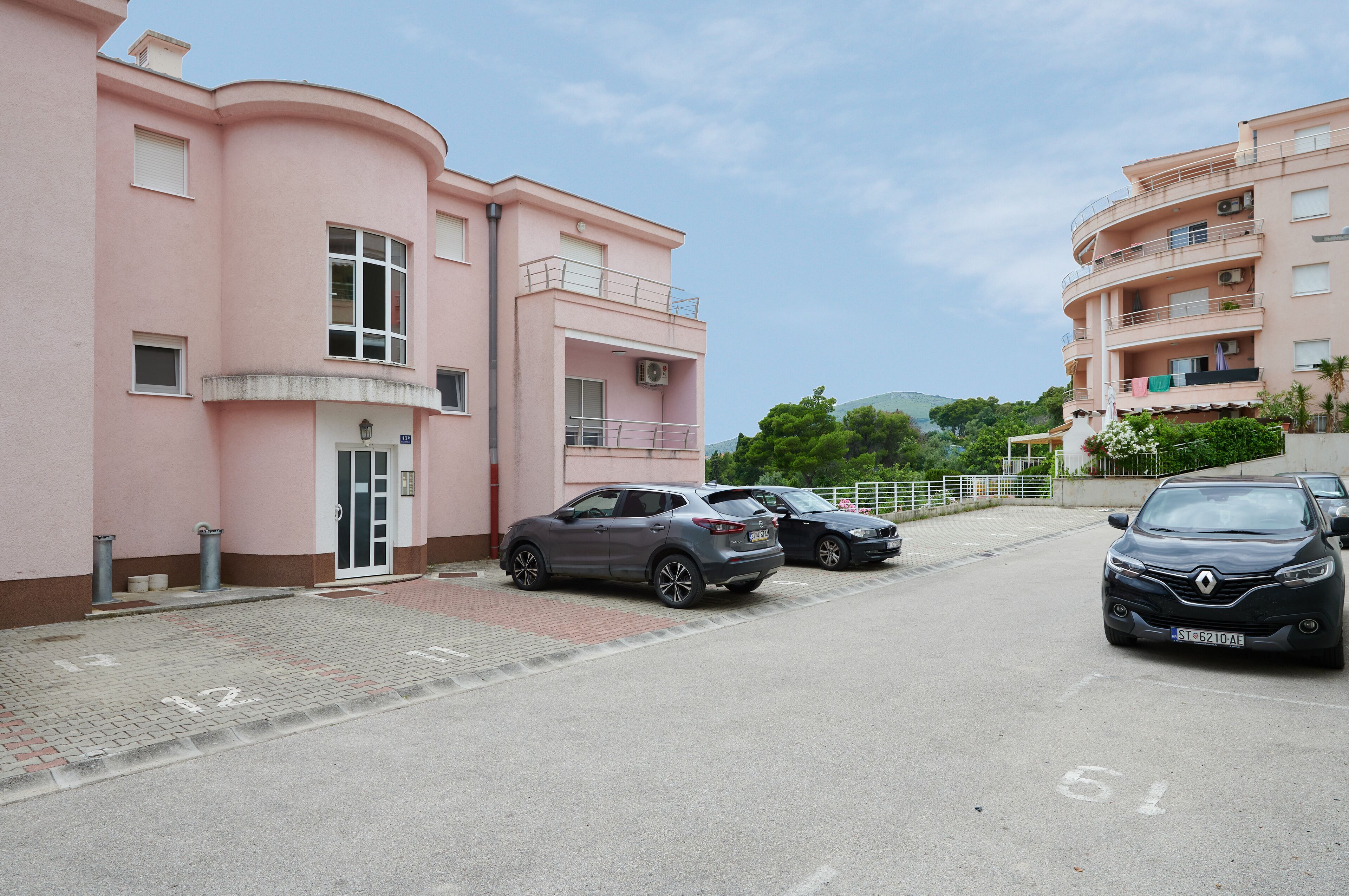 A pink building with a parking lot and two cars parked in front.