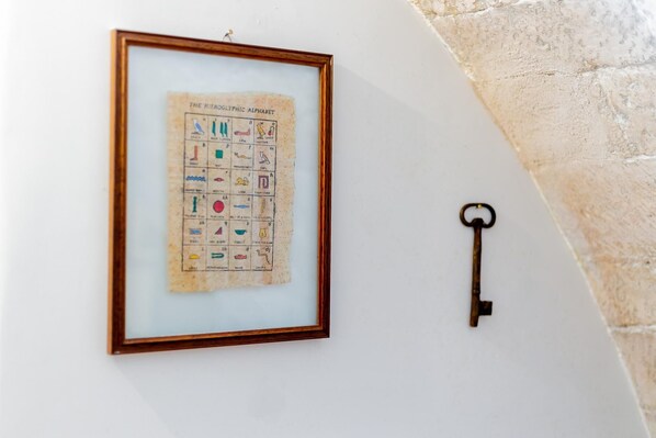A framed hieroglyphic alphabet chart and a key on a wall.
