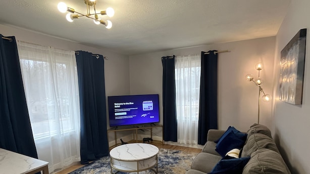 A modern living room with a flat-screen TV, a round coffee table, and a sofa.