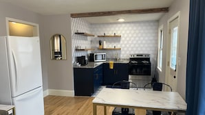 A compact kitchen with a refrigerator, microwave, stove, and dark blue cabinets.