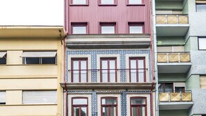 Een meerhoog gebouw met verschillende architectuurstijlen, waaronder een roze gevel met grote ramen en een gedeelte onderaan in blauw en wit patroon.
