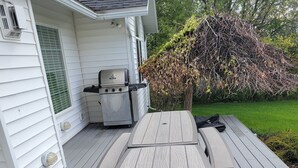 Un terrazzo in legno con tavolo da picnic e area barbecue.