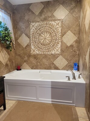 Un baño moderno con una bañera independiente, un azulejo decorativo en la pared y una planta en maceta.