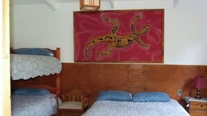 Un dormitorio con cabecera de madera, cama con colcha estampada, una silla y una obra de arte colgada en la pared.