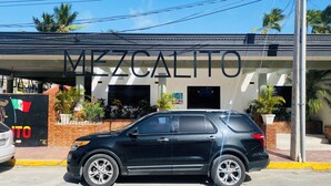 Ein schwarzer SUV vor einem Gebäude mit der Aufschrift 'MEXCALITO'.