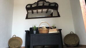 A room with a dark wicker bench, a wall-mounted mirror, and two wicker baskets. - Can Bonet de Baix Está Situada en el Centro de la Isla y Tiene Vistas al Campo (IB)