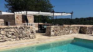 A rectangular pool with clear water, surrounded by stone walls and a pergola with white canopies. - Can Bonet de Baix Está Situada en el Centro de la Isla y Tiene Vistas al Campo (IB)
