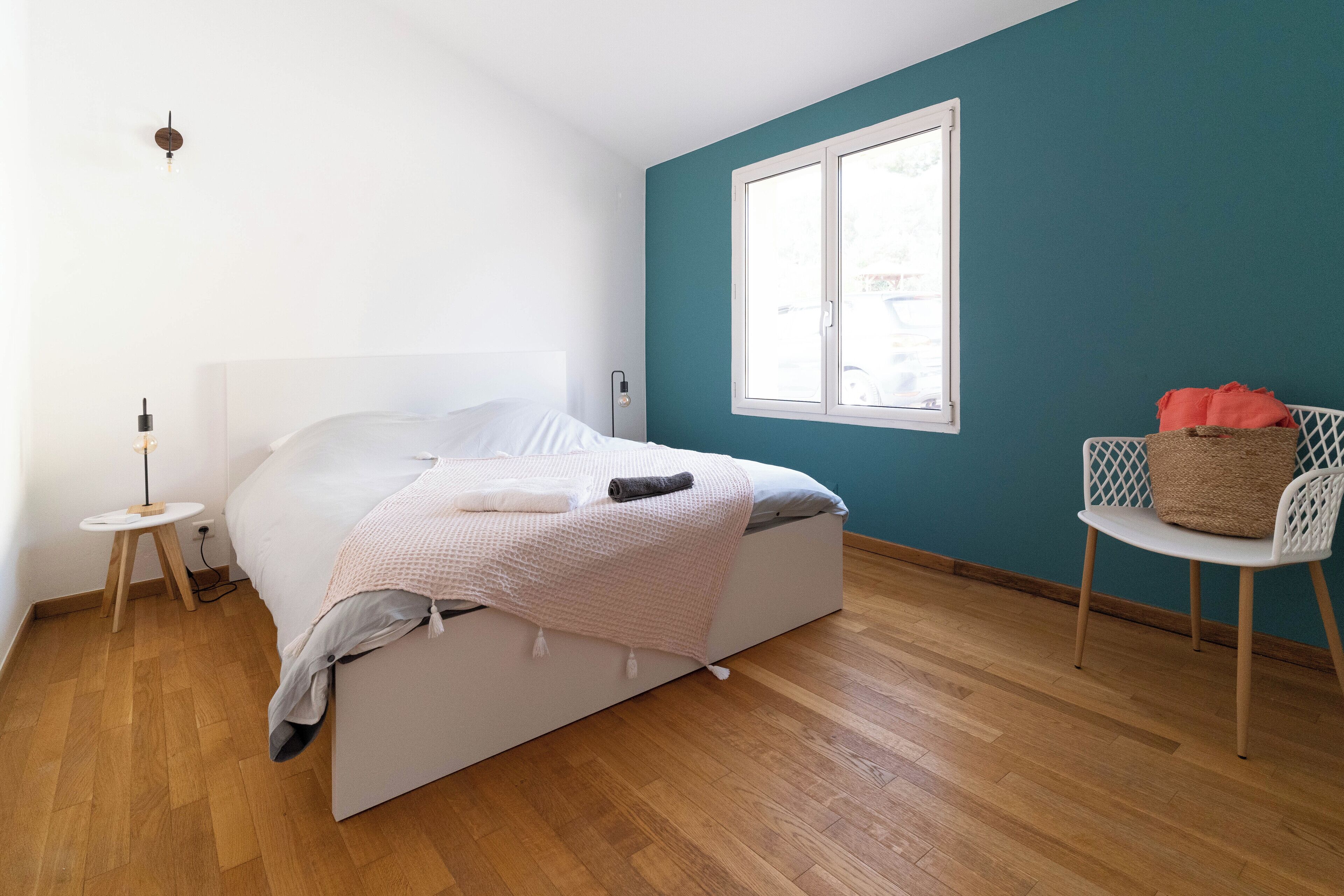 Une chambre à coucher avec un lit, une petite table, une chaise et une fenêtre.