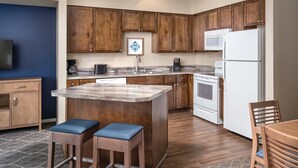 A modern kitchen with wooden cabinets, a central island, and a dining area with two stools. - Perfect Resort in Charming Solvang California (Solvang)