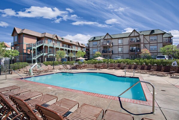 A pool area with lounge chairs and a clear blue pool.