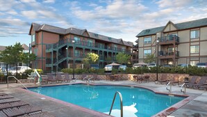 A swimming pool with lounge chairs and a building with balconies in the background.