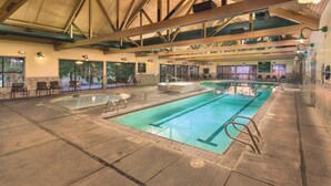 En indendørs swimmingpool med flere baner, siddepladser og et højt loft med synlige konstruktionsbjælker.