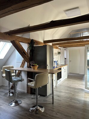 Eine moderne Küche mit Holzboden, einer zentralen Kochinsel mit Barhocker und einem eingebauten Kühlschrank.