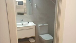 A small, compact bathroom with a white sink, toilet, and shower. - El Pico Sotombo (Ampuero)