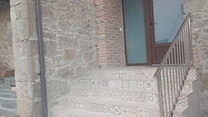 A stone building with a small window and a metal staircase leading to a door. - El Pico Sotombo (Ampuero)