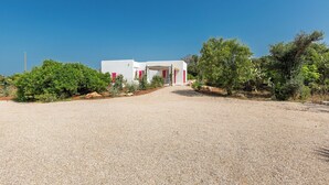Un bâtiment blanc agrémenté de touches de rouge, avec une allée de gravier menant à l’entrée.