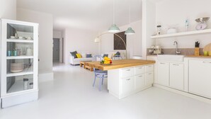 Une cuisine moderne avec des meubles blancs, un îlot central en bois et des luminaires suspendus.