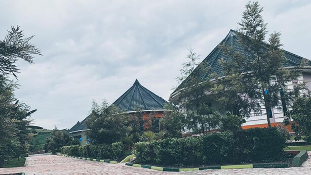 A courtyard with stone paving, two traditional-style buildings with tiled roofs, and surrounding greenery. - Bwizi Gardens and Resort (Mbarara)
