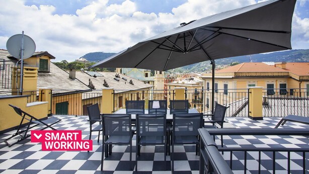 Terrassa al terrat amb sòl de pissos, mobiliari exterior i un gran para-sol.